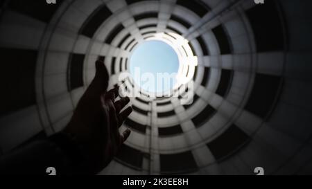 Tube d'entrée en spirale d'un garage de stationnement en béton avec vue sur le ciel bleu et les nuages blancs. Prise de vue grand angle de bas en haut Banque D'Images