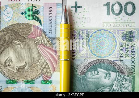Règlements financiers en Pologne, concept, billets 100 et 500 zlotys polonais empilés les uns à côté des autres, entre eux un stylo jaune, les impôts en Pologne, Banque D'Images