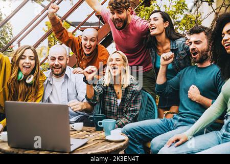 Des gens internationaux multiethniques qui célèbrent pour un objectif de regarder des contenus en streaming sur un ordinateur portable - excités divers amis appréciant a s Banque D'Images