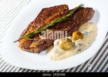 Steak de bœuf avec sauce aux champignons branche de romarin à l'assiette blanche Banque D'Images