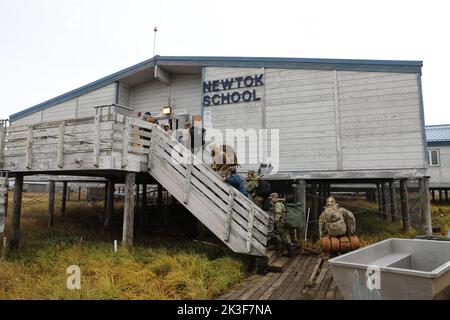 Des soldats américains de la Garde nationale de l'Alaska entrent dans l'école locale après l'atterrissage pour aider les résidents locaux à nettoyer après le typhon Merbok, 22 septembre 2022, à Newtok, en Alaska. Les villages autochtones éloignés de l'Alaska ont subi des inondations sur plus de 1 000 milles de côtes de l'Alaska. Banque D'Images