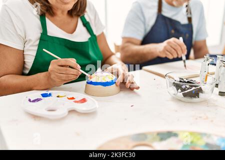 Peintre hispanique d'âge moyen peint en couple dans un studio d'art. Banque D'Images