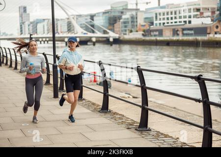 Deux femmes athlétiques en vêtements de sport sont en train de courir le long du remblai. Atteindre l'objectif Banque D'Images