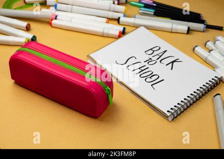 Retour à l'école est écrit en marqueur noir sur un bloc-notes blanc. Les fournitures scolaires sont préparées pour l'école Banque D'Images