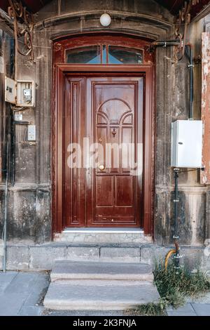 Ancienne maison classique en pierre avec porte en bois rustique, marron, sculptée et ancienne. Textures de porte et fond. Photo de haute qualité. Banque D'Images