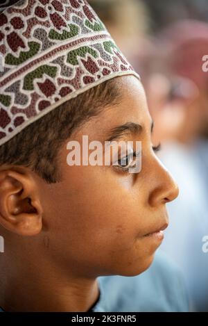 Jeune garçon avec kuma traditionnel (haine ronde omanaise) au marché du bétail du vendredi matin, Nizwa, Oman Banque D'Images