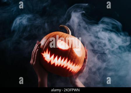 Citrouille à la vapeur riant à l'eau - tête de Jack-o-lanterne avec des yeux sculptés et des smilk méchants sur fond de fumée. Symbole de Halloween, trick or Treat. Banque D'Images