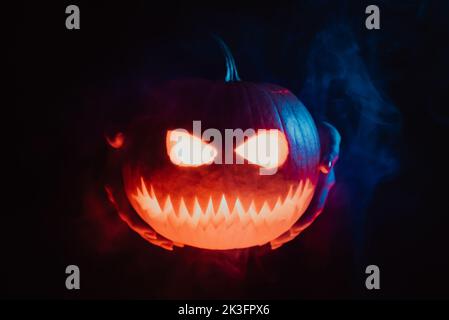 Tête de citrouille de jack-o-lanterne dans les mains sur fond de fumée noire. Symbole de Halloween, trick or Treat. Quelqu'un vous arnaque avec la gourde la nuit Banque D'Images