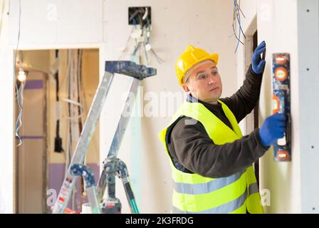Le constructeur vérifie la verticale de la paroi à l'aide du niveau Banque D'Images
