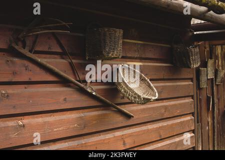 Vieux outils paysan accrochés sur un mur en bois sur une ferme animalière. Banque D'Images