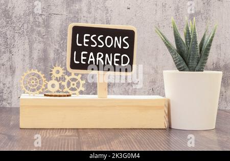 Sur la table se trouvent des crayons de couleur dans un support, des autocollants de couleur vive, des lunettes et un carnet avec les leçons d'inscription APPRISES. Banque D'Images