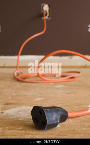 Rallonge électrique orange sur le sol en contreplaqué à l'intérieur de la maison. Banque D'Images