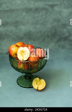 Pommes rouges fraîches dans un vase en verre sur fond gris Banque D'Images