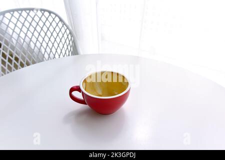 vue de dessus de la tasse vide rouge de café sur la table blanche dans le café matin, la lumière est magnifique. concept de café sale tasse après boisson. Banque D'Images