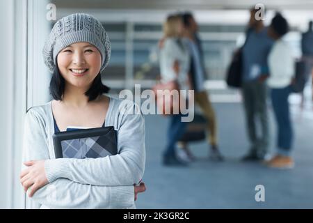 Je veux la meilleure éducation disponible. Portrait d'un étudiant d'université asiatique souriant avec des amis en arrière-plan. Banque D'Images