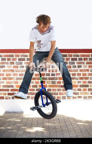 Rotation des sièges. Prise de vue en longueur d'un jeune homme à cheval sur un monocycle. Banque D'Images