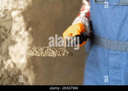 Mains homme plâtrier ouvrier de construction au travail avec truelle, plâtrage d'un mortier de ciment de mur, gros plan Banque D'Images