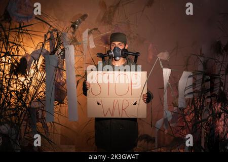 Protection de l'environnement. Un homme dans un masque à gaz tient une affiche avec le mot Stop War dans la fumée. Concept de protection de l'environnement. Pollution de l'air. Nocif Banque D'Images