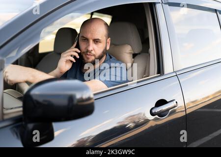 Homme conduisant sa voiture parlant sur le téléphone portable. Transport et véhicule Banque D'Images