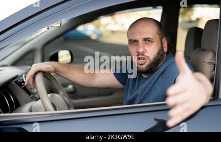 Homme irrité conduisant une voiture. Conducteur irrité sur route Banque D'Images