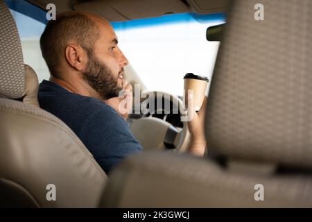 Homme tenant une tasse de papier à café en voiture. Profitez d'une tasse de café à emporter pour vous concentrer sur votre travail Banque D'Images