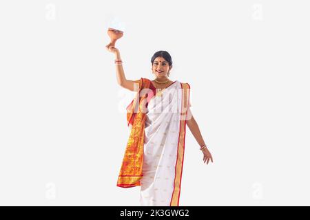 Portrait d'une femme bengali qui exécute la danse Dhunuchi sur fond blanc Banque D'Images