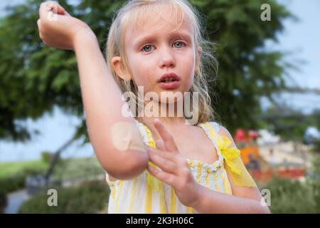 Petite fille. Blessure au coude. Tombé dans le parc lors d'une promenade, montre une blessure et des cris Banque D'Images