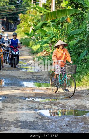 Cycliste portant un chapeau de bambou sur la route de campagne, Hai Phong rural, Vietnam Banque D'Images