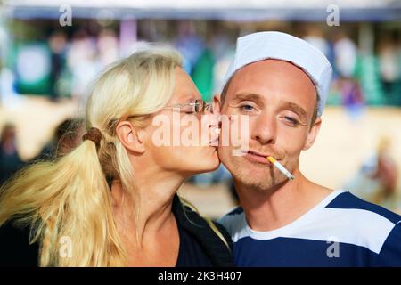 Personne ne pouvait résister au marin. Une femme embrassant un gars dans une tenue de marin à un festival de musique. Banque D'Images