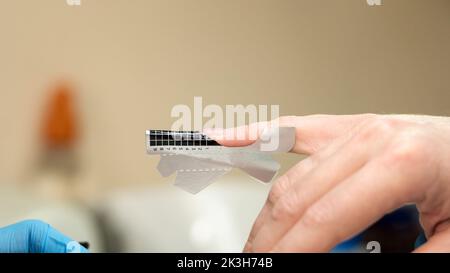 La construction de clous de beauté. Extensions de clou inférieures. Le maître manucure dans le salon de beauté vérifie si les formulaires papier pour l'extension d'ongle installé uniformément fem Banque D'Images