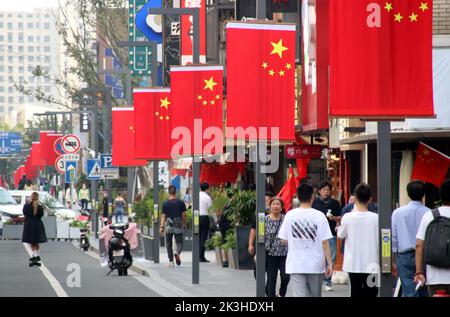 SUZHOU, CHINE - le 26 SEPTEMBRE 2022 - les gens passent sous les drapeaux nationaux suspendus sur la rue Huaihai à Suzhou, province du Jiangsu, Chine, le 27 septembre 2022. Banque D'Images