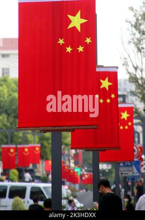 SUZHOU, CHINE - le 26 SEPTEMBRE 2022 - les gens passent sous les drapeaux nationaux suspendus sur la rue Huaihai à Suzhou, province du Jiangsu, Chine, le 27 septembre 2022. Banque D'Images