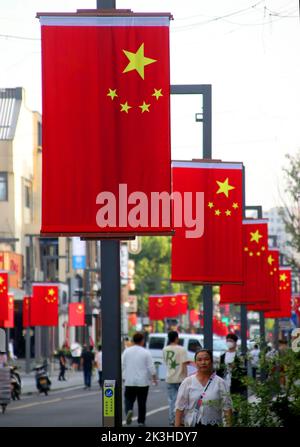 SUZHOU, CHINE - le 26 SEPTEMBRE 2022 - les gens passent sous les drapeaux nationaux suspendus sur la rue Huaihai à Suzhou, province du Jiangsu, Chine, le 27 septembre 2022. Banque D'Images