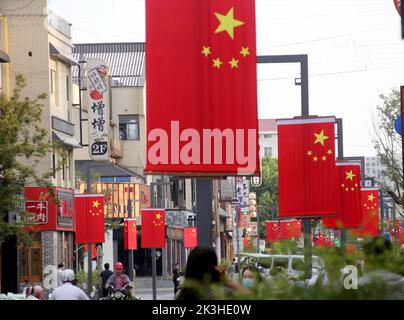 SUZHOU, CHINE - le 26 SEPTEMBRE 2022 - les gens passent sous les drapeaux nationaux suspendus sur la rue Huaihai à Suzhou, province du Jiangsu, Chine, le 27 septembre 2022. Banque D'Images