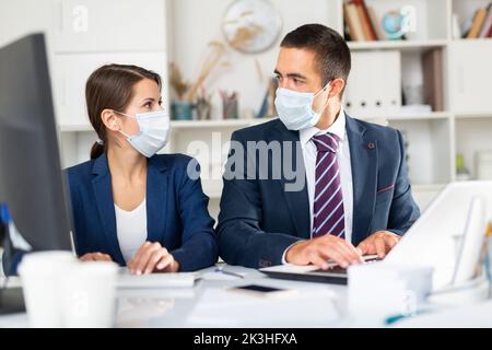 Les partenaires d'affaires hommes et femmes dans les masques de travail au bureau Banque D'Images