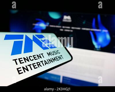 Smartphone avec le logo de la société chinoise Tencent Music Entertainment Group à l'écran devant le site Web d'affaires. Mise au point à gauche de l'écran du téléphone. Banque D'Images