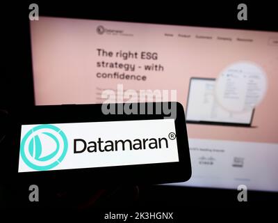 Personne tenant un smartphone avec le logo de la société britannique de logiciels ESG Dataran Ltd. À l'écran devant le site Web. Mise au point sur l'affichage du téléphone. Banque D'Images
