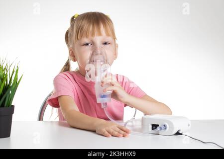 Belle petite fille respirant dans un inhalateur pour l'asthme et la pneumonie à la maison. Traitement des maladies des voies respiratoires supérieures chez les enfants. Co Banque D'Images