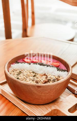 Délicieux petit déjeuner sain, bol à smoothie aux fraises avec granola, fruits, graines de chia et noix de coco, une photo esthétique sur fond clair. Banque D'Images