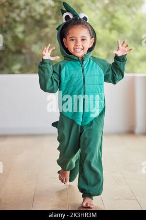 Costume créatif, enfant et halloween par fille courir dans un costume de crocodile, jouer et rire à la maison. Fantaisie, heureux et visage d'un enfant excité à Banque D'Images