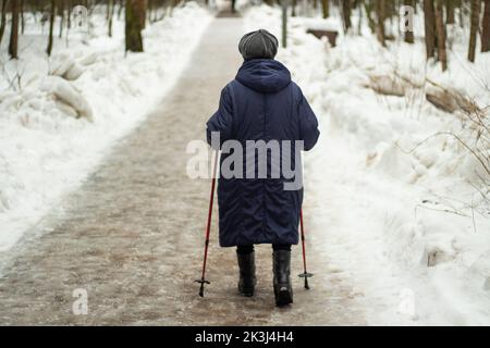 Granny avec bâtons de marche en hiver. Femme à la retraite. Le pensionné se promène dans le parc. Marche saine. Banque D'Images