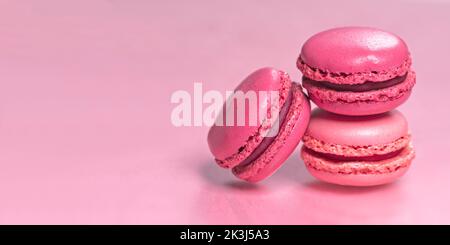 Macarons multicolores sur fond rose. Image panoramique avec espace de copie. Banque D'Images