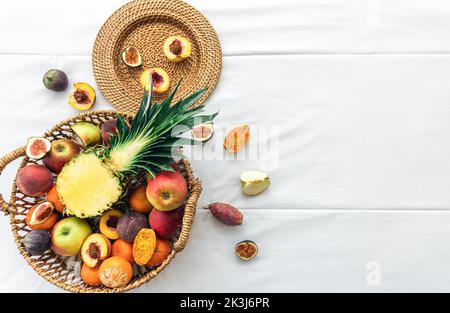 Ananas et autres fruits exotiques dans un panier sur fond blanc, vue de dessus. Banque D'Images