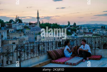 Couple heureux avec un verre sur le toit d'une maison de grotte village historique d'Ayvalii Goreme Cappadocia, couple regarder le coucher du soleil Kapadokya. Banque D'Images