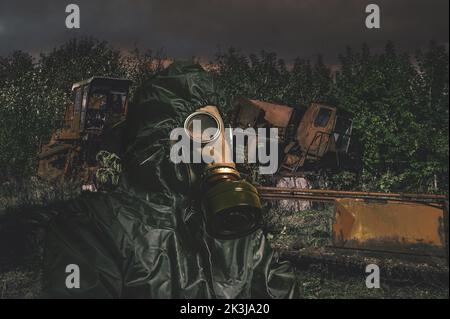 Un homme dans un masque à gaz et une combinaison de protection chimique sur fond de paysage post-apocalyptique Banque D'Images