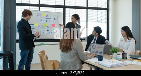 Groupe de collègues divers discutant pour rapport financier avec présentation sur tableau de conférence lors d'une petite conférence au bureau Banque D'Images