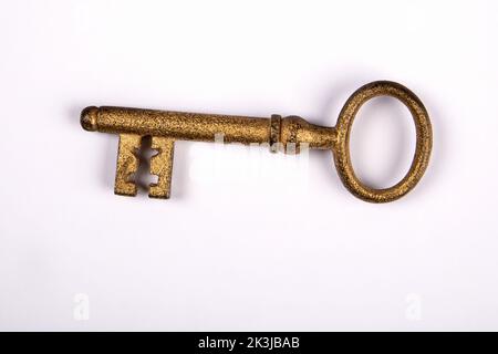 Ancienne clé de porte dorée sur fond blanc. Banque D'Images