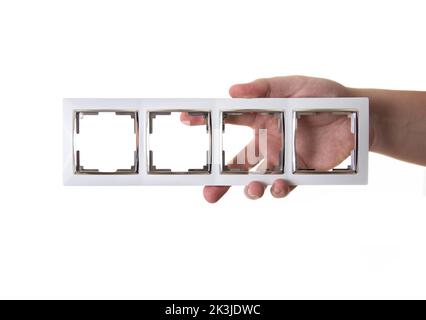 Un homme tient un cadre pour les prises électriques dans sa main sur un fond blanc, isoler. Banque D'Images