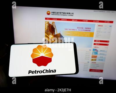 Personne tenant un smartphone avec le logo du pétrole et du gaz chinois PetroChina Company Limited à l'écran devant le site Web. Mise au point sur l'affichage du téléphone. Banque D'Images