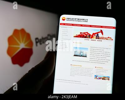 Personne tenant un téléphone portable avec le site Web de pétrole et de gaz chinois PetroChina Company Limited à l'écran avec le logo. Concentrez-vous sur le centre de l'écran du téléphone. Banque D'Images